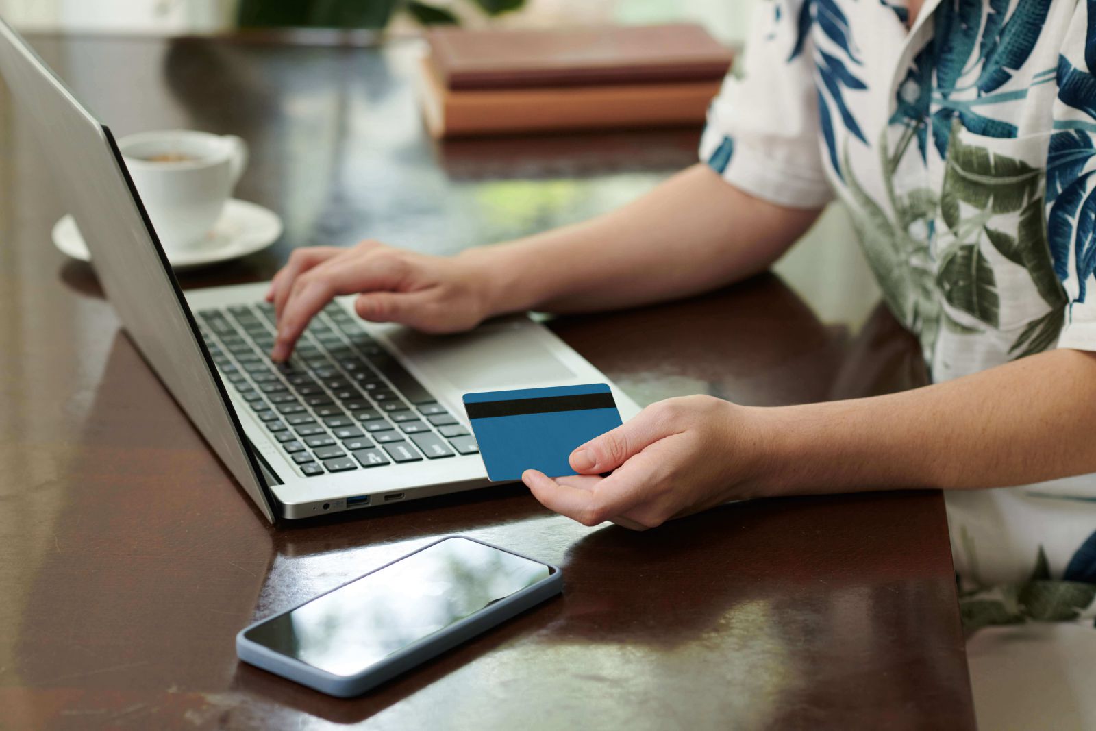 Person holding card with laptop in other hand