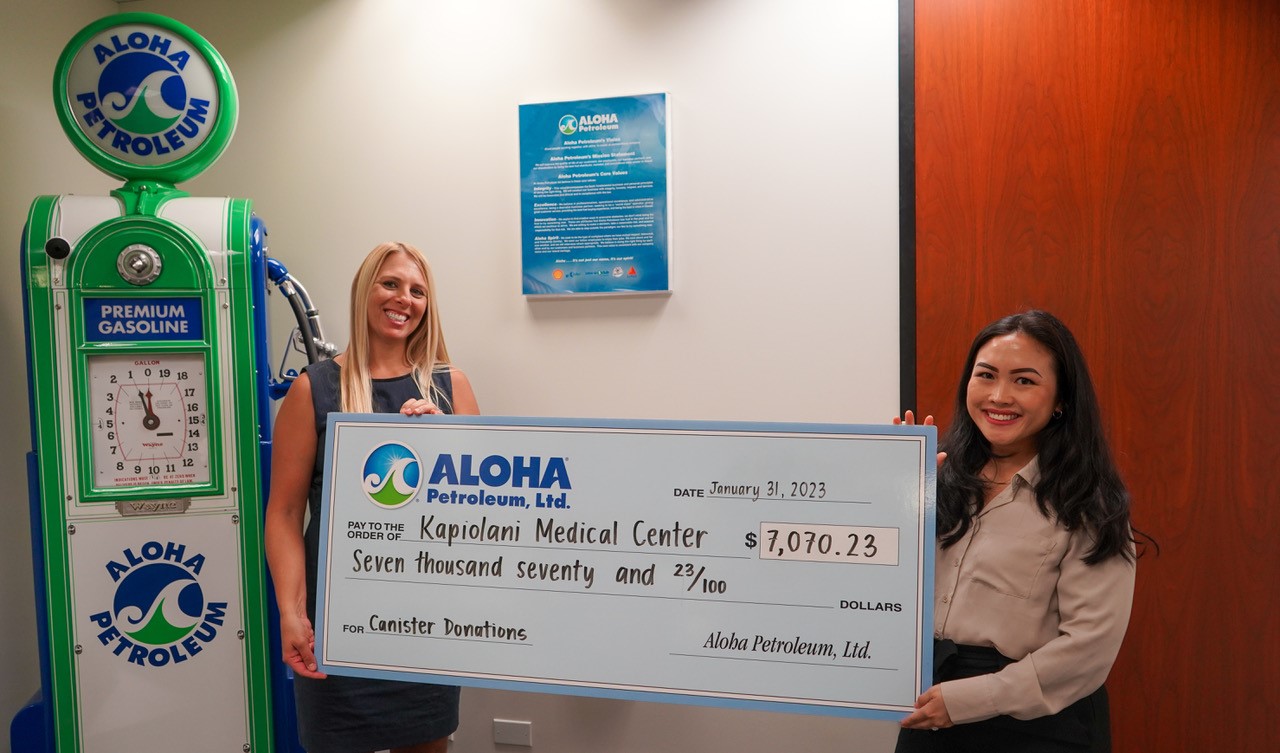 Aloha representative hands check to medical center employee.